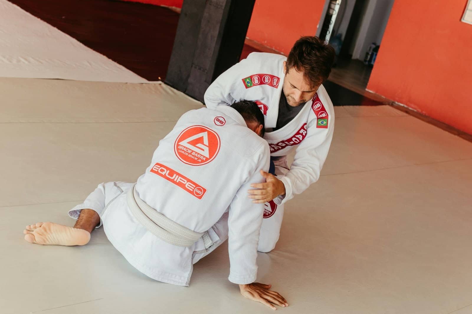Dois adultos iniciantes em posição de treino de Jiu-Jitsu no tatame